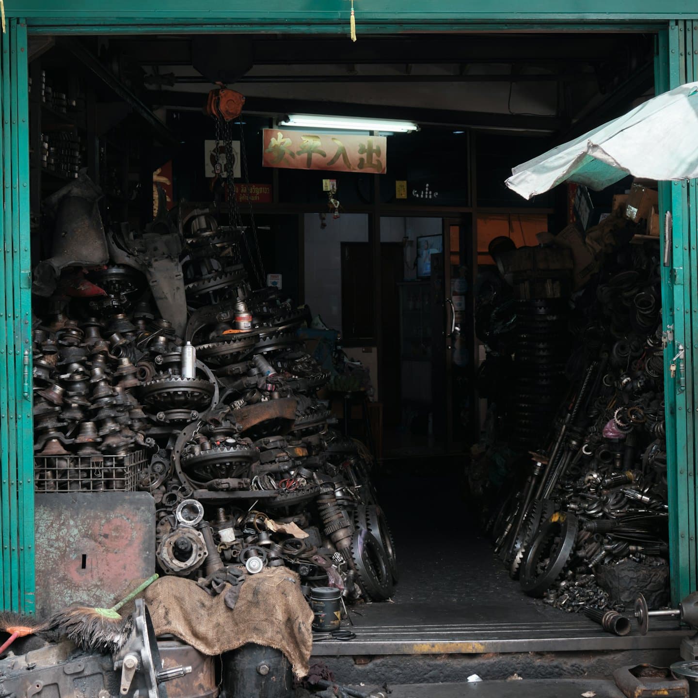 Cluttered auto parts shop interior with piles of engine components.